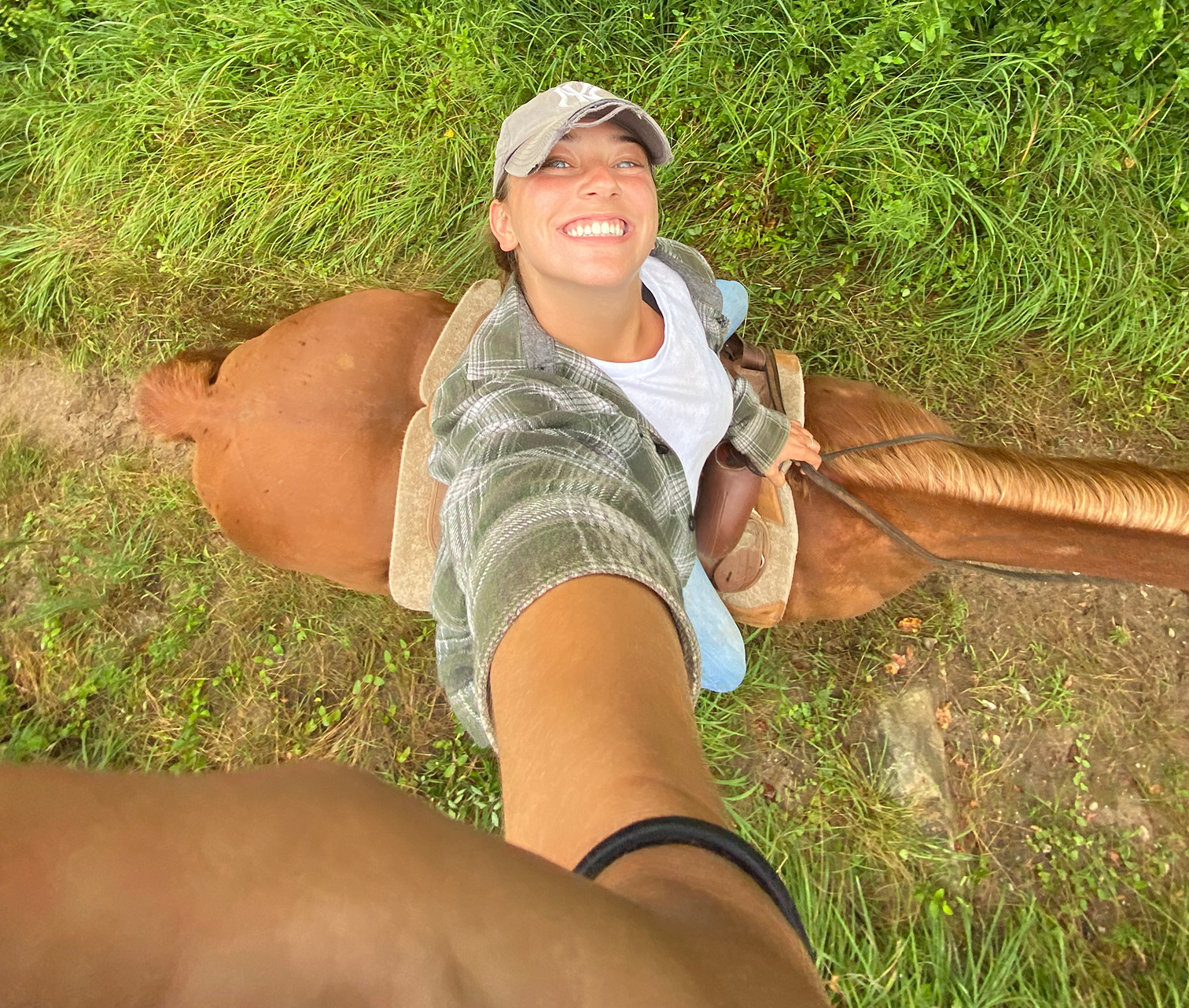 A woman on horseback smiles up at the camera
